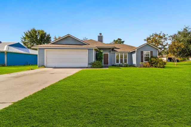 a front view of a house with a garden and trees