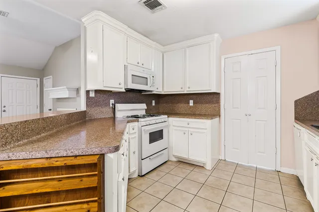 a kitchen with granite countertop white cabinets and white appliances