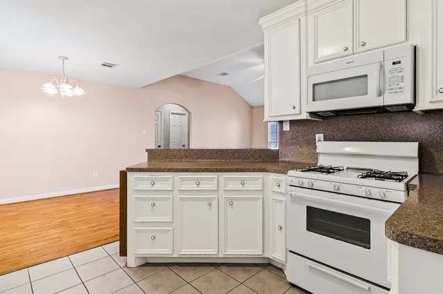 a kitchen with granite countertop white cabinets and white appliances