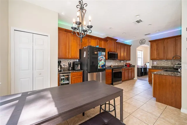 a kitchen with stainless steel appliances granite countertop a refrigerator a sink dishwasher a stove and white cabinets with wooden floor