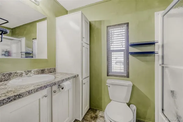 a bathroom with a granite countertop toilet sink and mirror