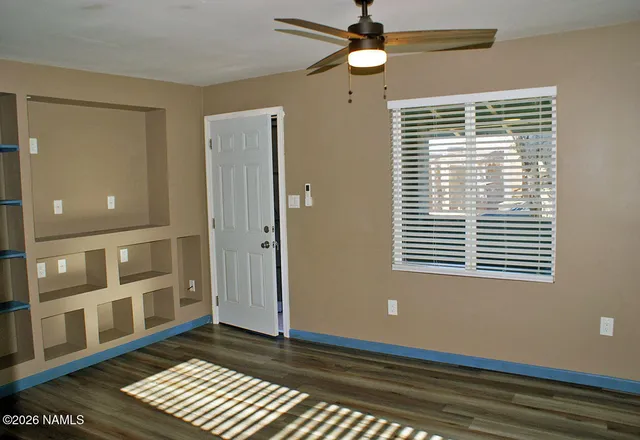 a view of an empty room with a window and wooden floor