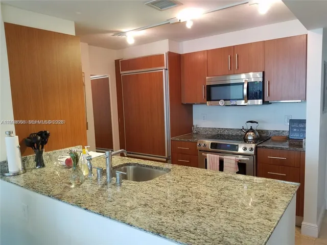 a kitchen with stainless steel appliances granite countertop a sink refrigerator and microwave
