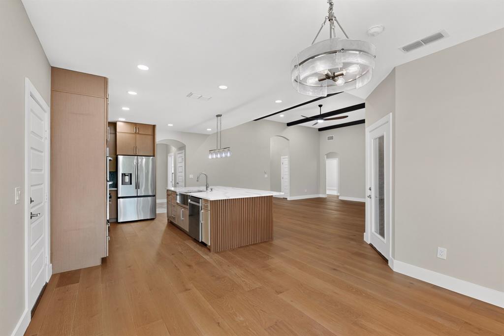 108 Winding Way Azle, TX 76020 - Photo 21 of 38 Open-concept living space featuring wood-finish flooring, a kitchen island with a farmhouse sink, stainless steel appliances, and a vaulted ceiling with exposed beams
