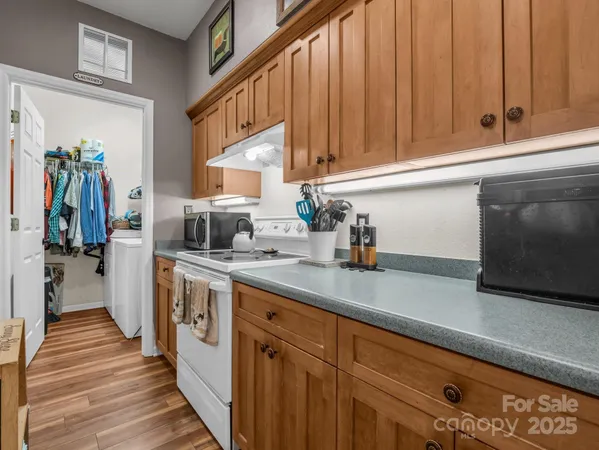 a kitchen with stainless steel appliances granite countertop a sink a stove and a wooden cabinets