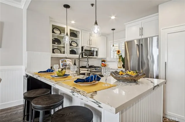 a kitchen with a appliances a stove a kitchen island and chairs with wooden floor