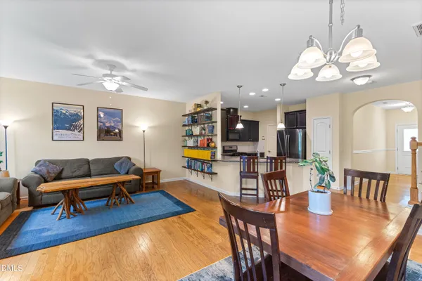 a living room with dining table a chandelier a dining table and chairs with wooden floor