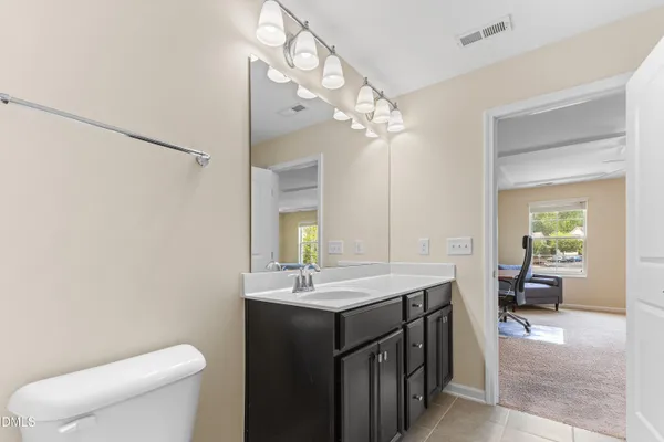 a spacious bathroom with a granite countertop sink a toilet a mirror and shower