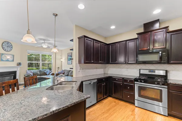 a kitchen with stainless steel appliances granite countertop a sink a stove and a wooden floors