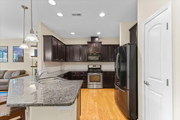 a kitchen with stainless steel appliances granite countertop a sink refrigerator and cabinets