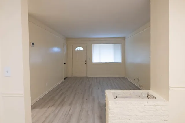 a view of an empty room with wooden floor and a window