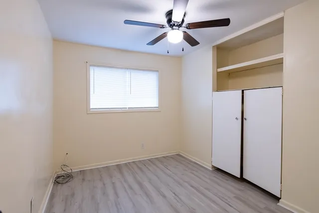 an empty room with wooden floor closet and windows
