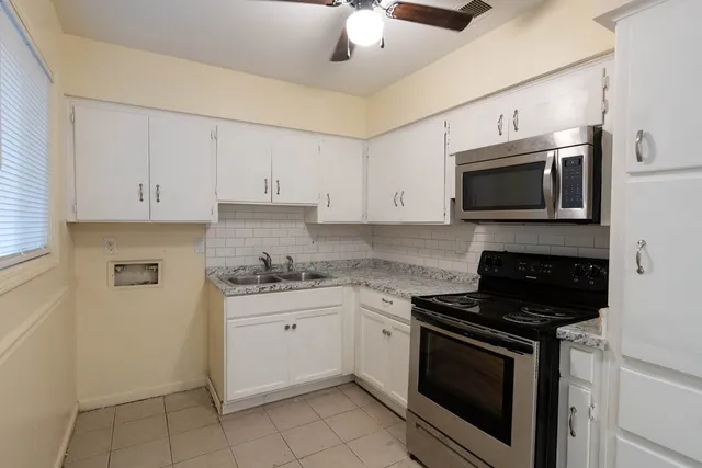 a kitchen with granite countertop white cabinets stainless steel appliances and a sink