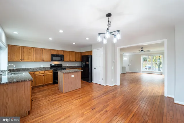 a kitchen with stainless steel appliances granite countertop wooden floors and white cabinets