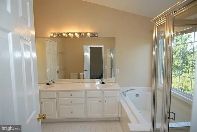 a spacious bathroom with a double vanity sink a large mirror and a bathtub