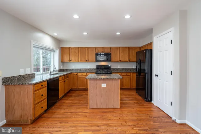 a large kitchen with stainless steel appliances granite countertop a stove a sink dishwasher and a refrigerator