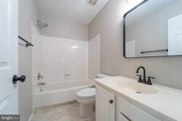 a bathroom with a toilet a sink a mirror a bathtub and vanity