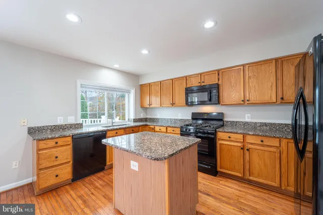 a kitchen with granite countertop a sink stove cabinets and wooden floor