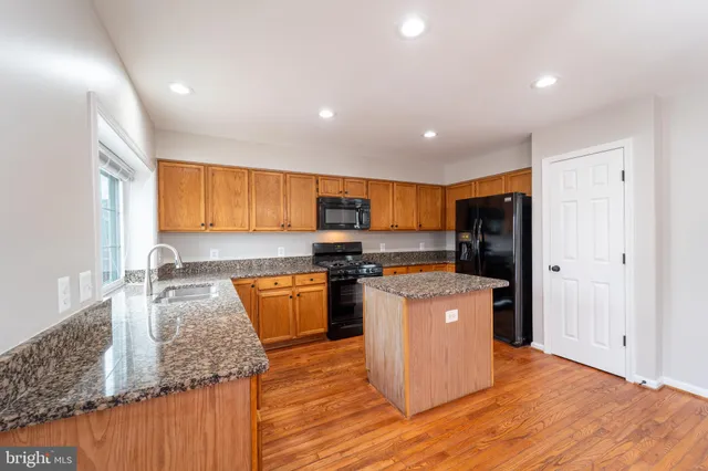 a kitchen with stainless steel appliances granite countertop a refrigerator a stove top oven a sink and dishwasher with wooden floor