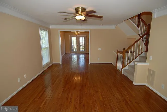 a view of empty room with wooden floor and fan