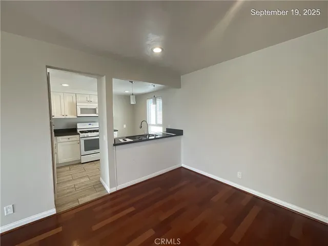a kitchen with stainless steel appliances granite countertop a sink a stove a refrigerator and white cabinets