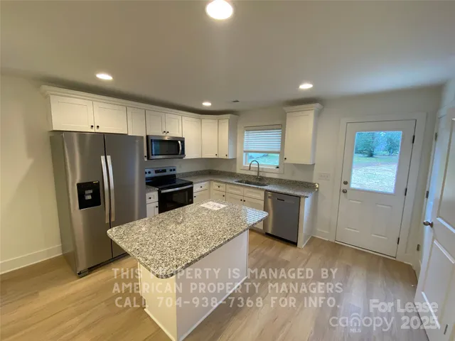 a kitchen with a refrigerator a sink a stove a microwave and island