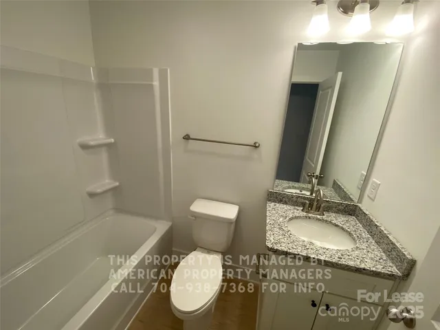 a bathroom with a granite countertop sink toilet and a mirror