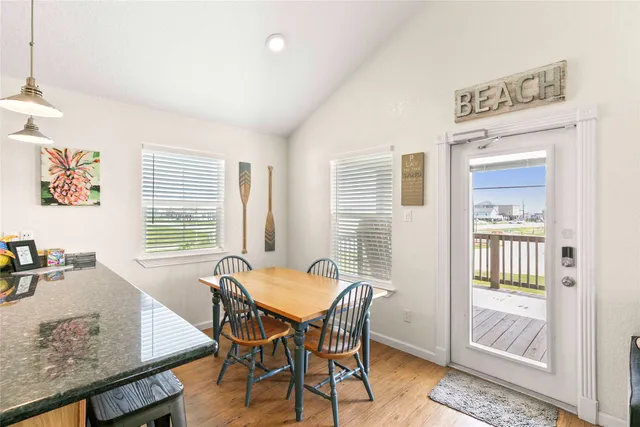 a kitchen with stainless steel appliances granite countertop a refrigerator a stove a sink a dining table and chairs with wooden floor