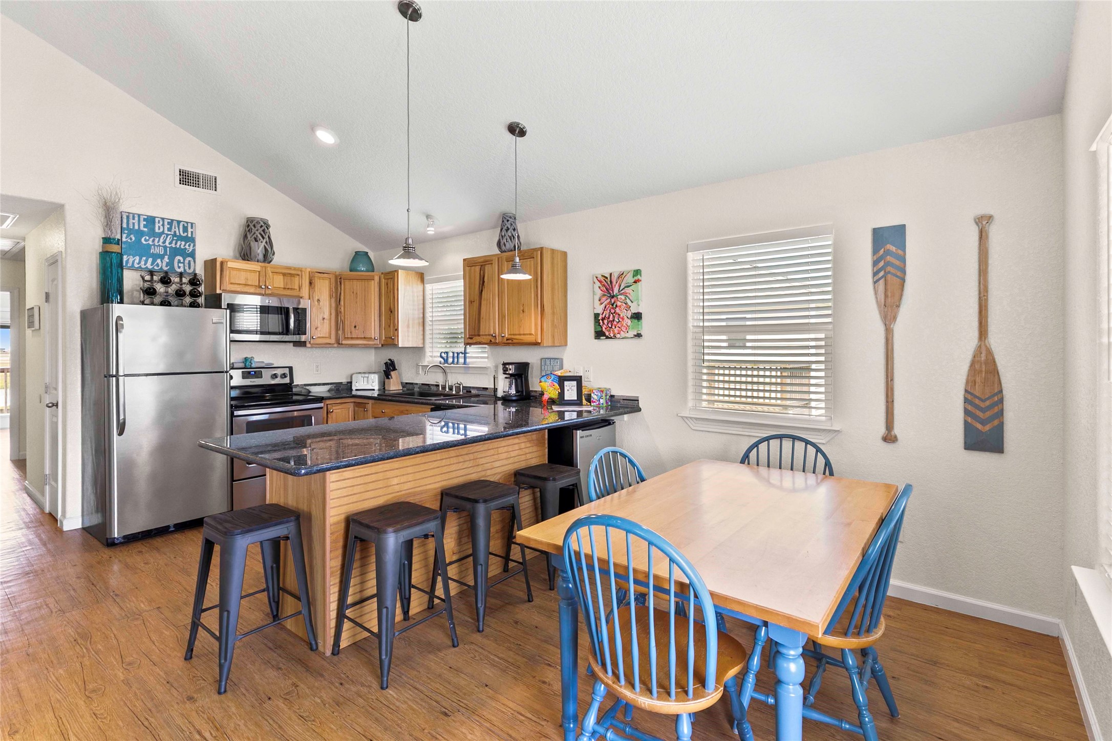 757 Bluewater Highway Surfside Beach, TX 77541 - Photo 15 of 44 a kitchen with stainless steel appliances granite countertop a refrigerator a stove a sink a dining table and chairs with wooden floor