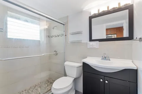 a bathroom with a sink a toilet a mirror and shower