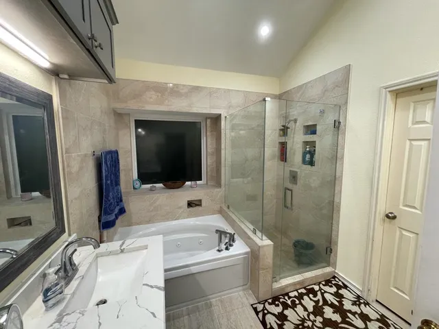 a bathroom with a tub a sink and a large mirror