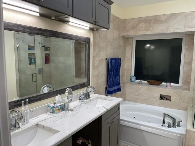 a bathroom with a sink a large mirror and a bathtub