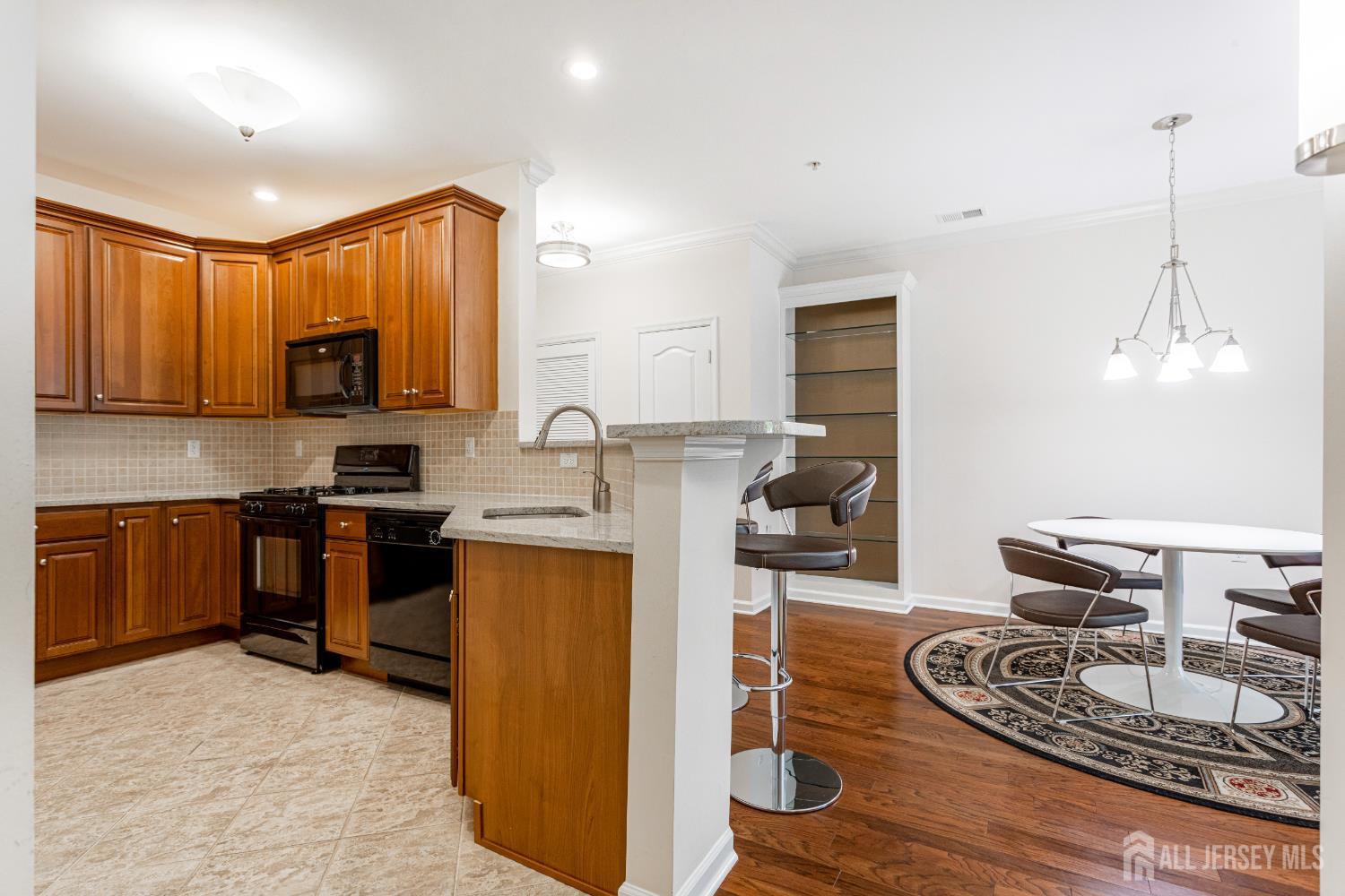 40 Azalea Drive Old Bridge, NJ 08857 - Photo 10 of 35 a kitchen with kitchen island granite countertop wooden cabinets a stove a sink and a dining table with wooden floor