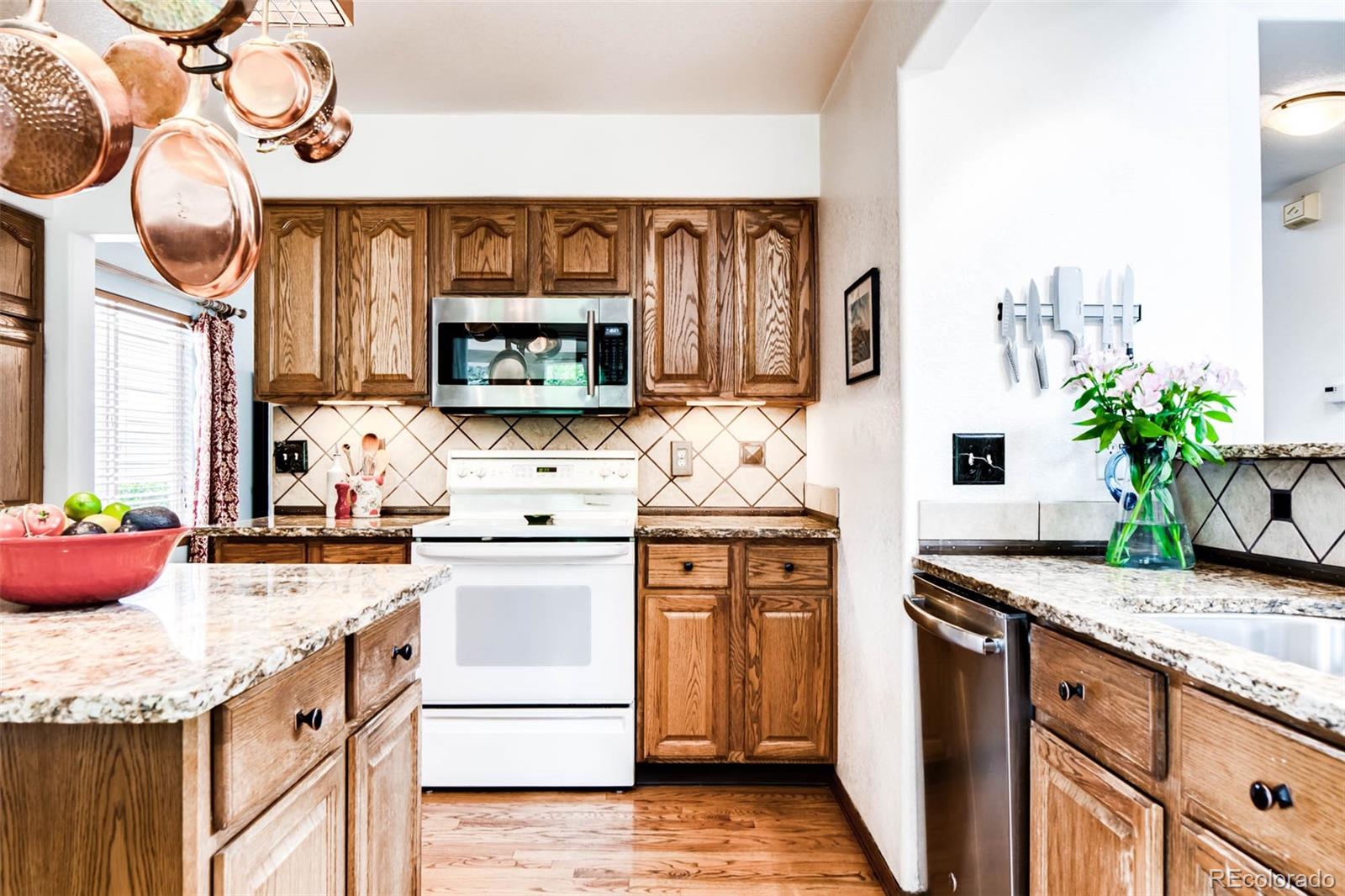 6549 Poppy Street Arvada, CO 80007 - Photo 7 of 33 a kitchen with stainless steel appliances granite countertop a sink and cabinets