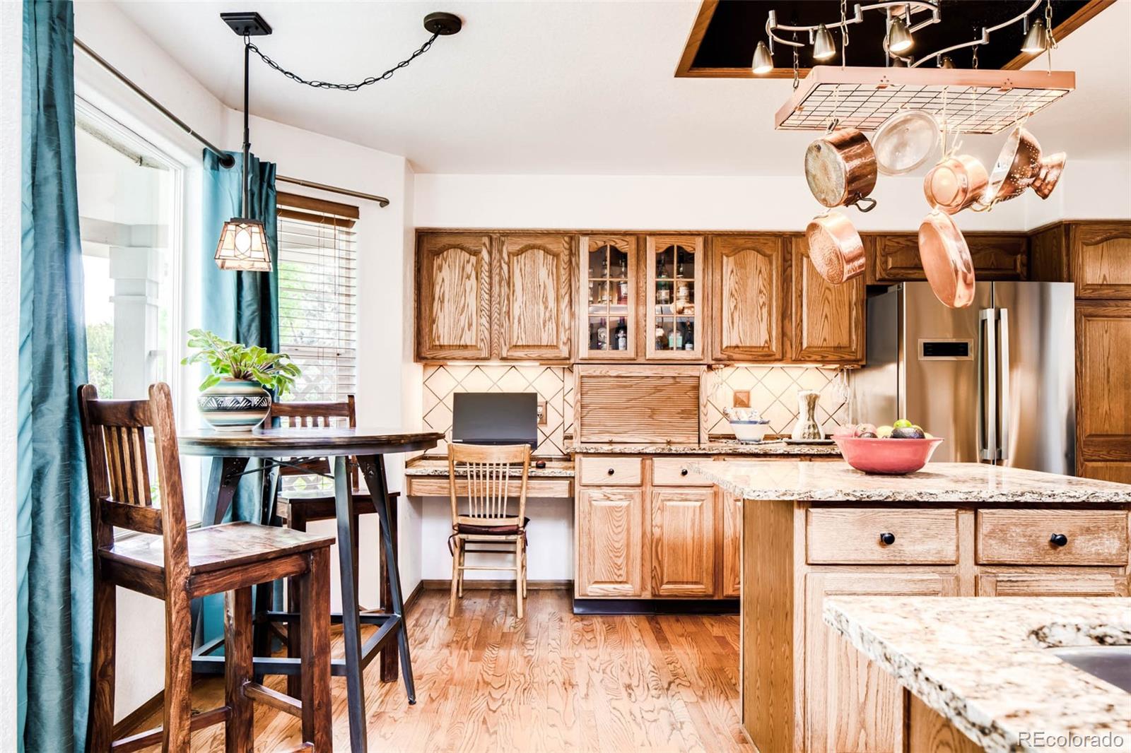 6549 Poppy Street Arvada, CO 80007 - Photo 8 of 33 a kitchen with stainless steel appliances kitchen island granite countertop a table chairs in it and wooden floors