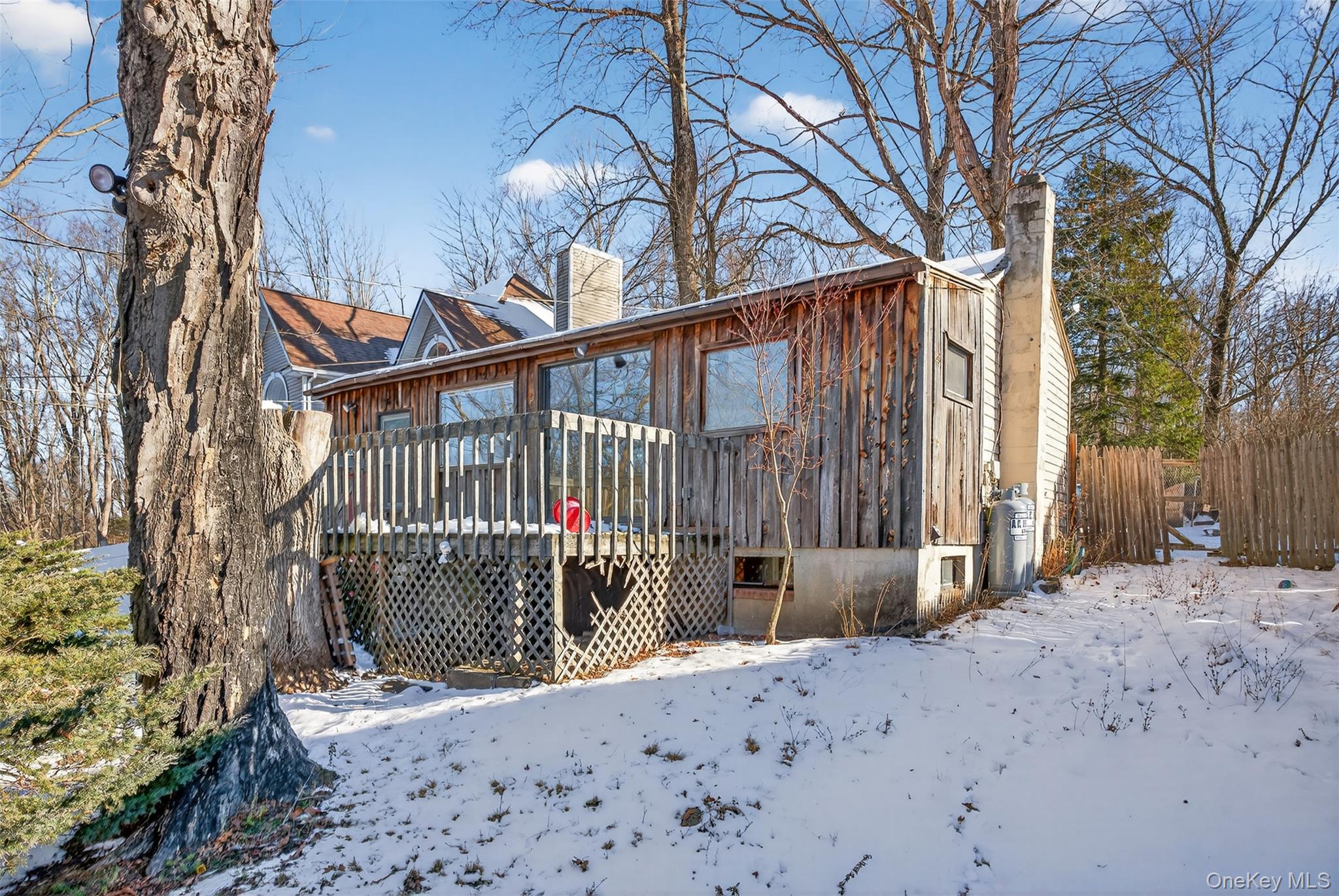 a view of a backyard with wooden fence and large trees