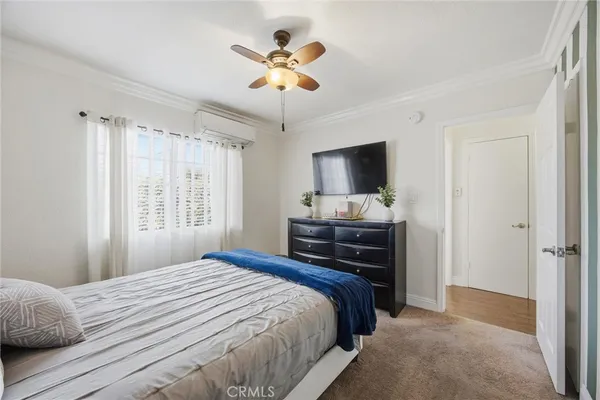 a bedroom with a bed and a flat tv screen on dresser
