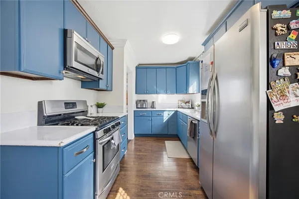 a kitchen with stainless steel appliances granite countertop a stove a sink dishwasher a refrigerator and a microwave oven with wooden floor