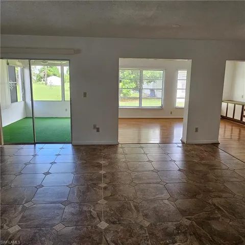 a view of an empty room with window and wooden floor