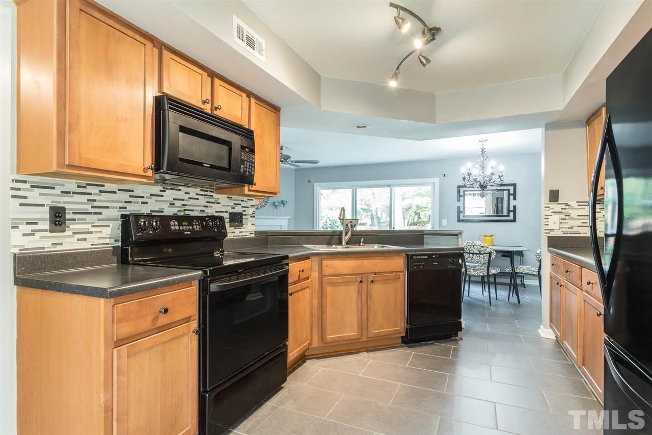 7615 Falcon Rest Circle, Unit 7615 Raleigh, NC 27615 - Photo 19 of 26 a kitchen with stainless steel appliances granite countertop a stove top oven a sink dishwasher a dining table and chairs with wooden floor