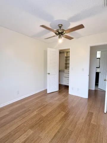 an empty room with wooden floor ceiling fan and windows