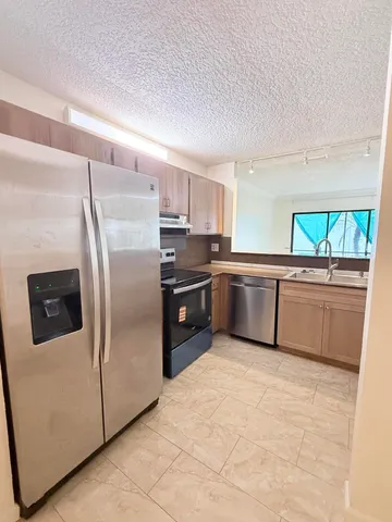 a kitchen with stainless steel appliances a refrigerator sink and stove