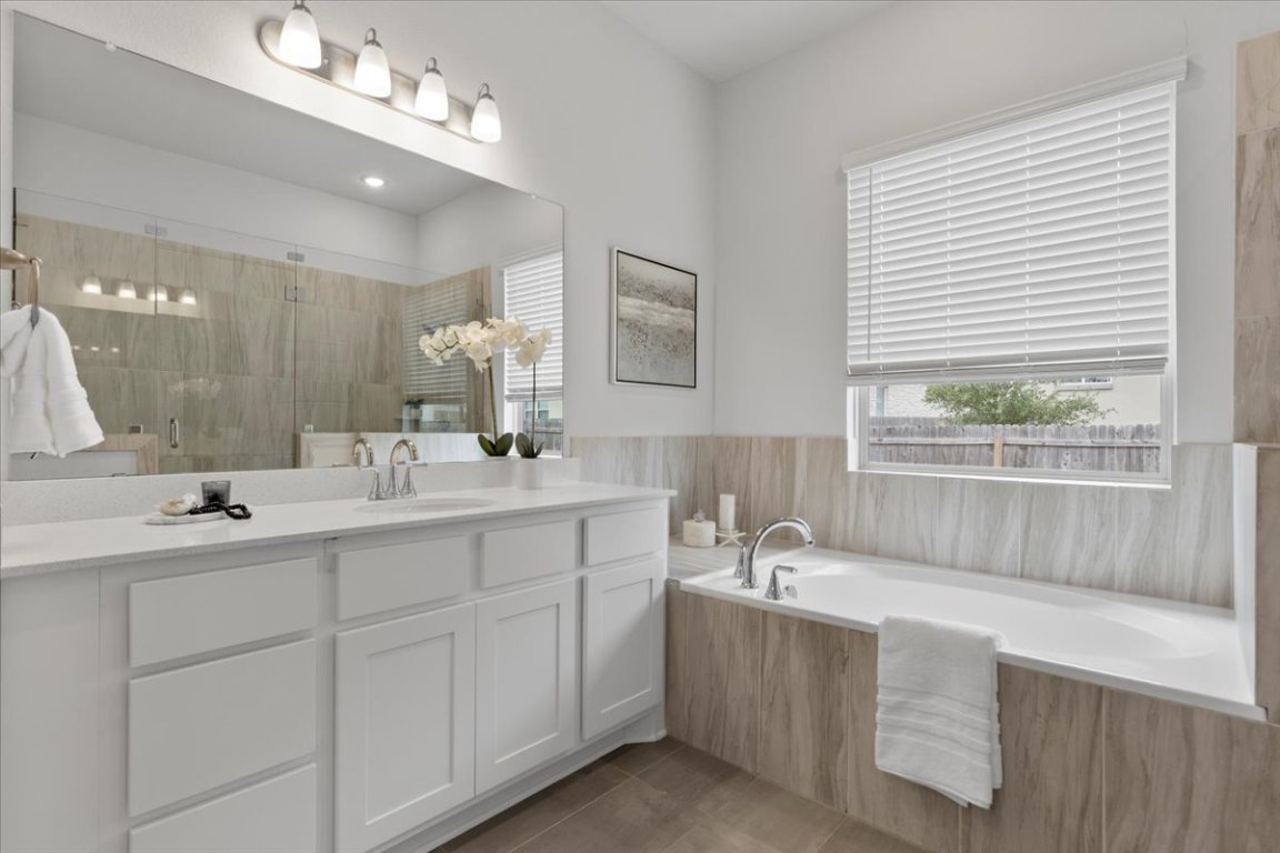 271 Eclipse Drive Austin, TX 78737 - Photo 16 of 39 a bathroom with double vanity sinks a large mirror and a bathtub