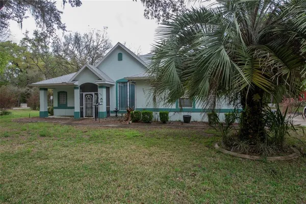 a front view of a house with a garden and trees