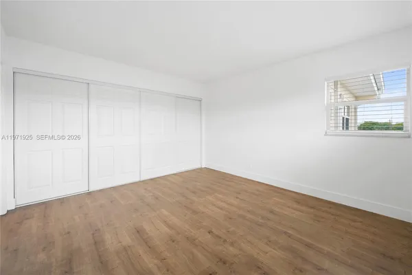 a view of empty room with wooden floor