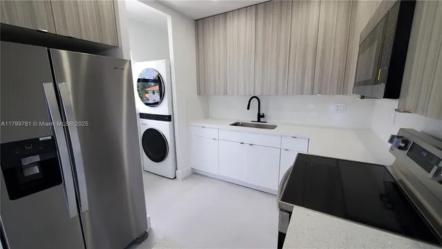 a kitchen with stainless steel appliances a refrigerator a sink a stove and white cabinets