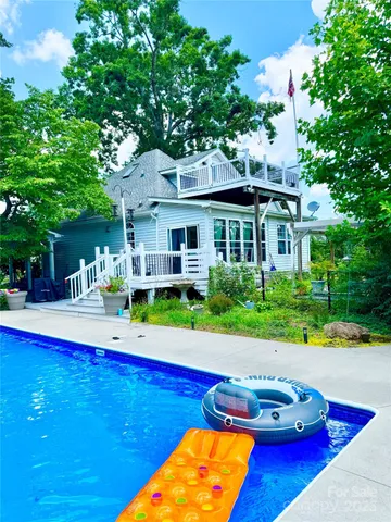 a front view of house and yard with swimming pool and green space
