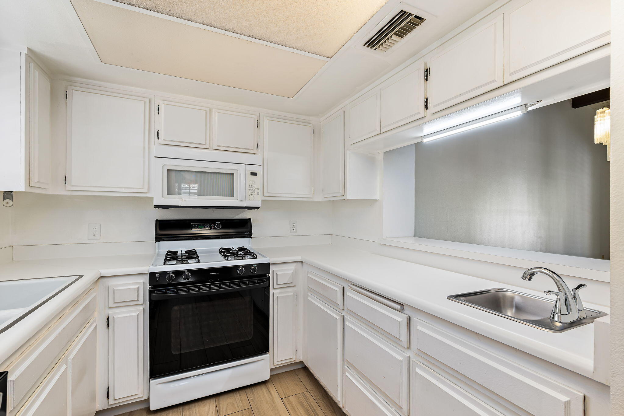 1150 East Palm Canyon Drive, Unit 37 Palm Springs, CA 92264 - Photo 13 of 40 a kitchen with white cabinets and black appliances