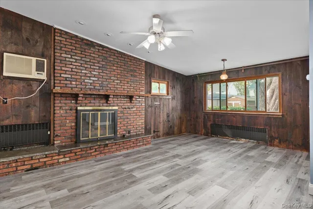 a view of an empty room with wooden floor and a fireplace