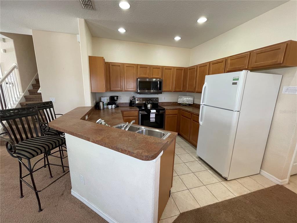 141 Summer Pl Loop Clermont, FL 34714 - Photo 13 of 63 a kitchen with a refrigerator a stove top oven a sink and cabinets